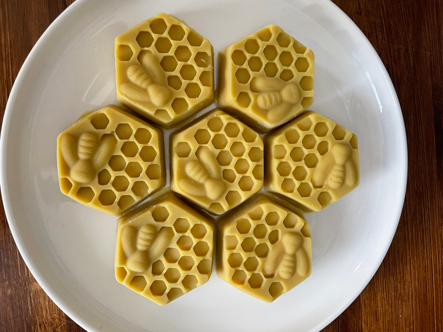 Hexagonal honeycomb and bee-shaped honey soaps on a white plate