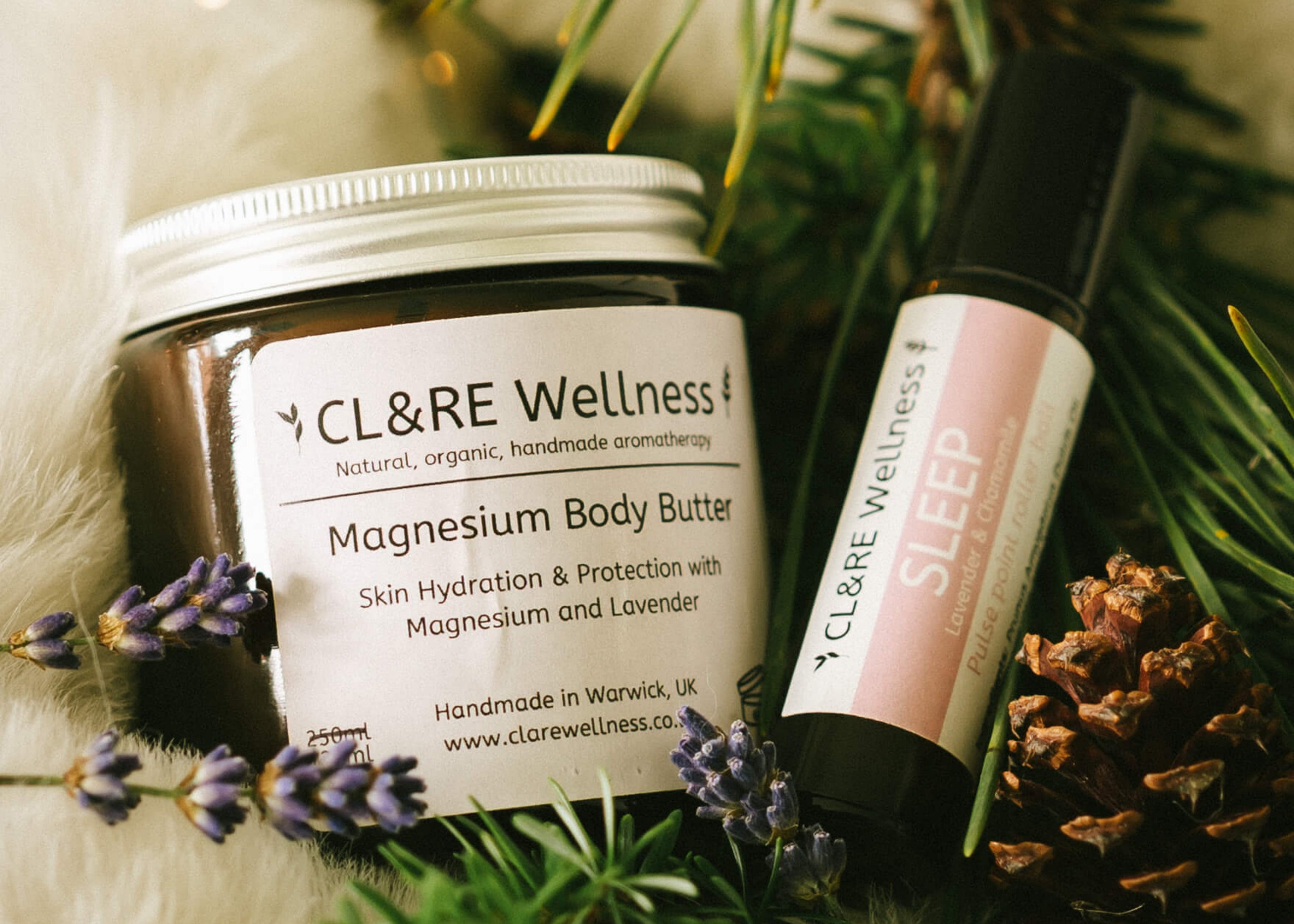 CL&RE Wellness magnesium body butter and sleep rollerball on a decorative background with greenery and lavender.