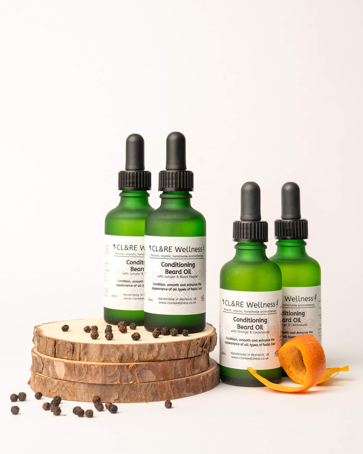Four green bottles of CLARE Wellness Conditioning Beard Oil on a white background