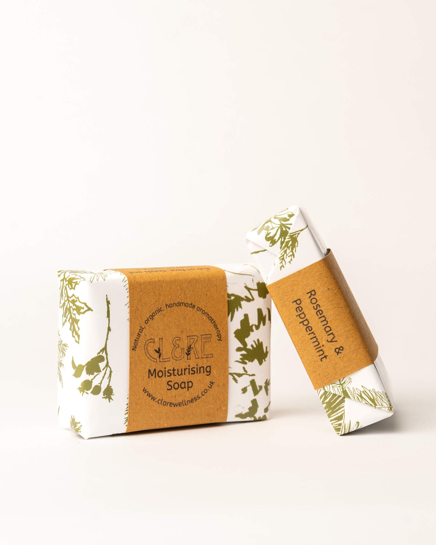 Two bars of CL&RE Wellness soap with green leaf patterns on a white background