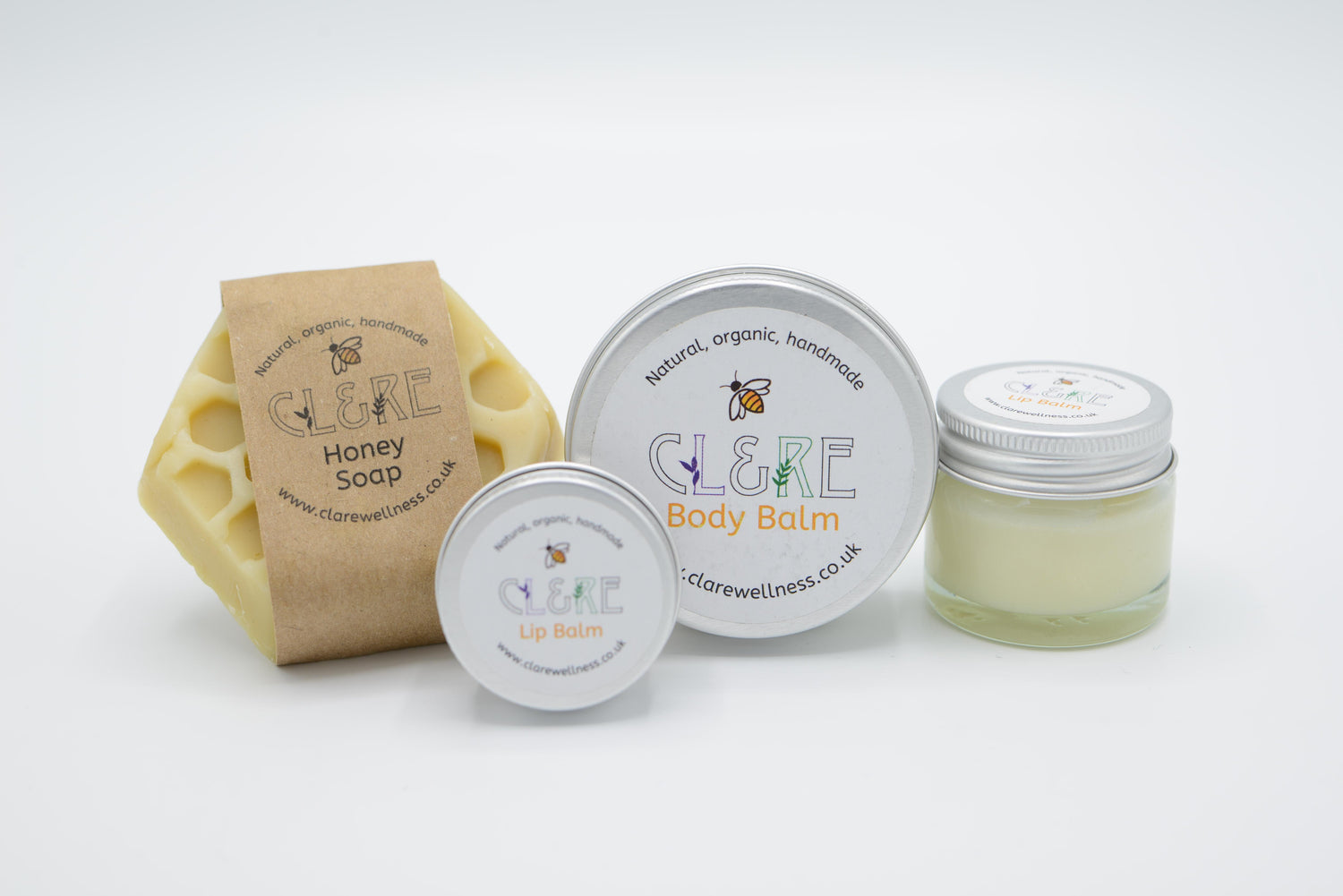 A collection of a CL&RE Wellness Honey Soap, Honey Body Balm and 2 Lip Balms on a white background