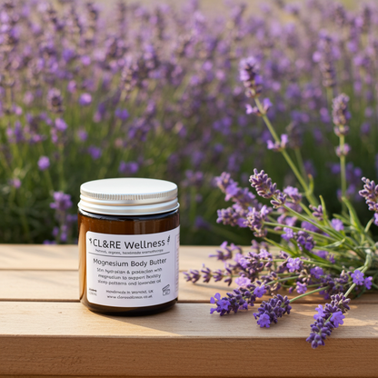 Jar of CL&RE Wellness magnesium body butter with lavender flowers on a wooden surface and lavender field in the background